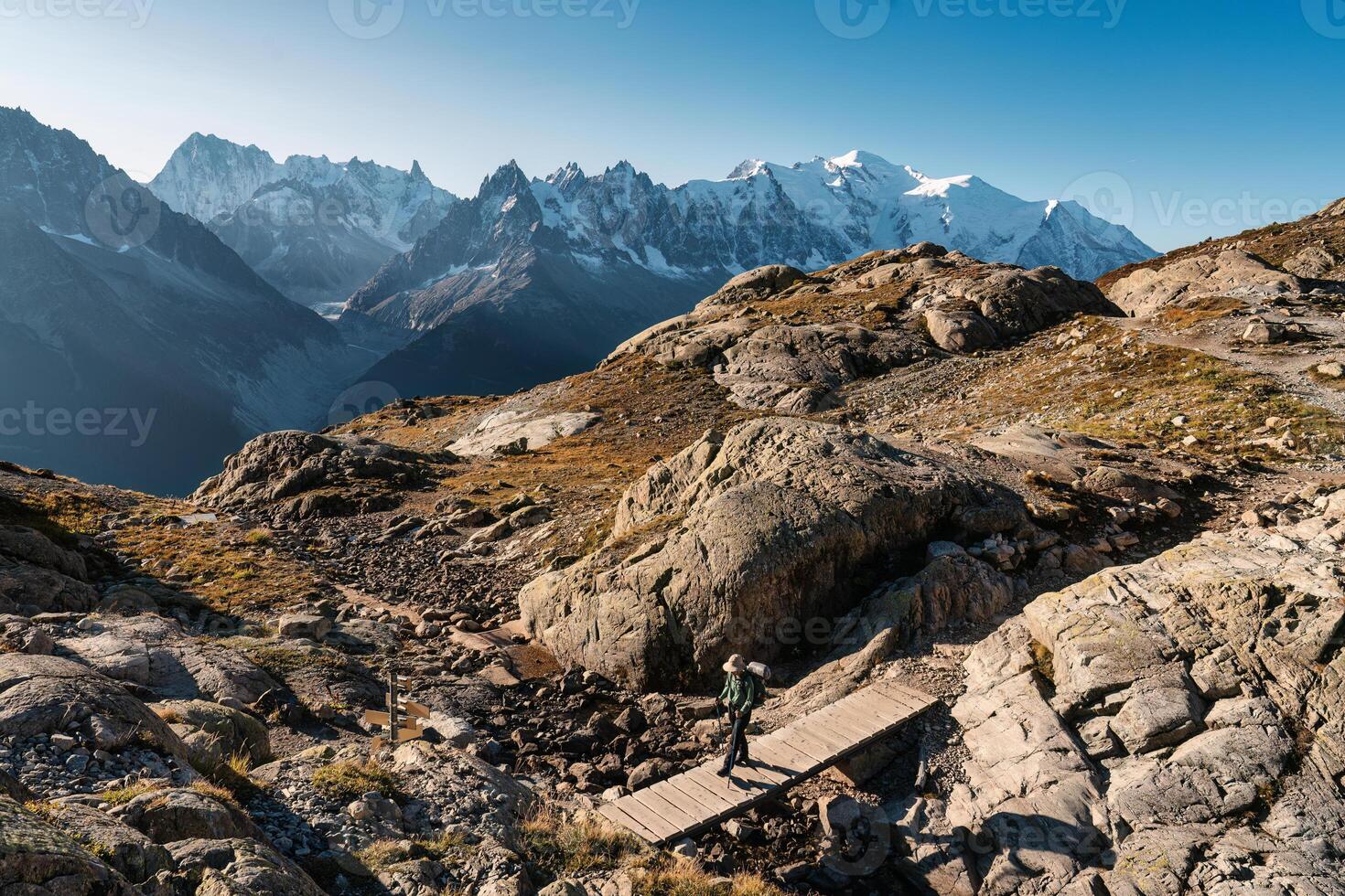 Woman with backpack hiking with Mont Blanc massif in French Alps on trail of Lac Blanc at France photo