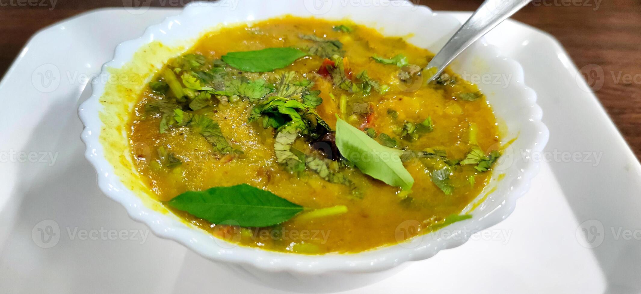 Traditional south indian snack dal sambhar soup with curry leaves photo