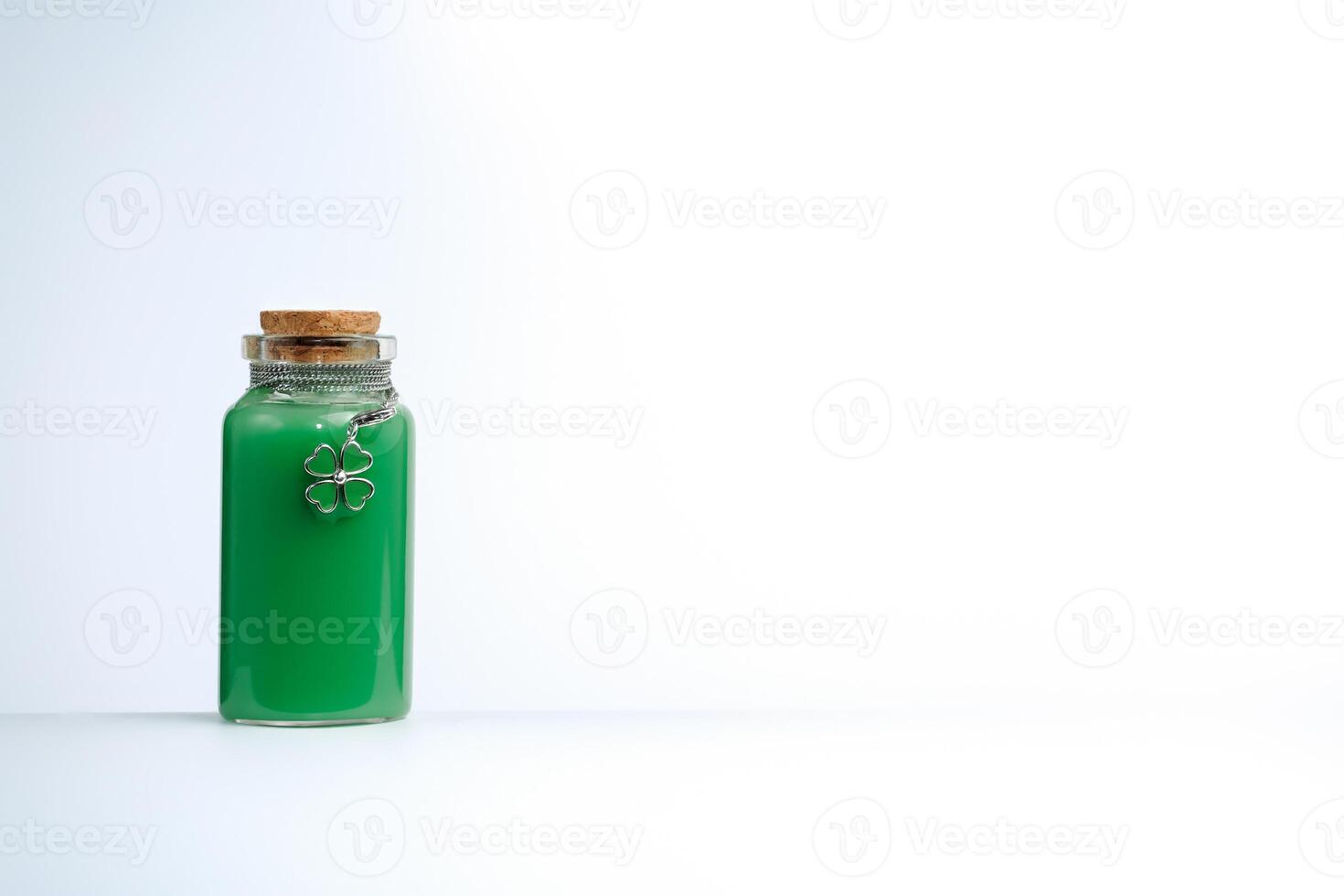 Phial with green liquid and four leaf clover shamrock on white background photo