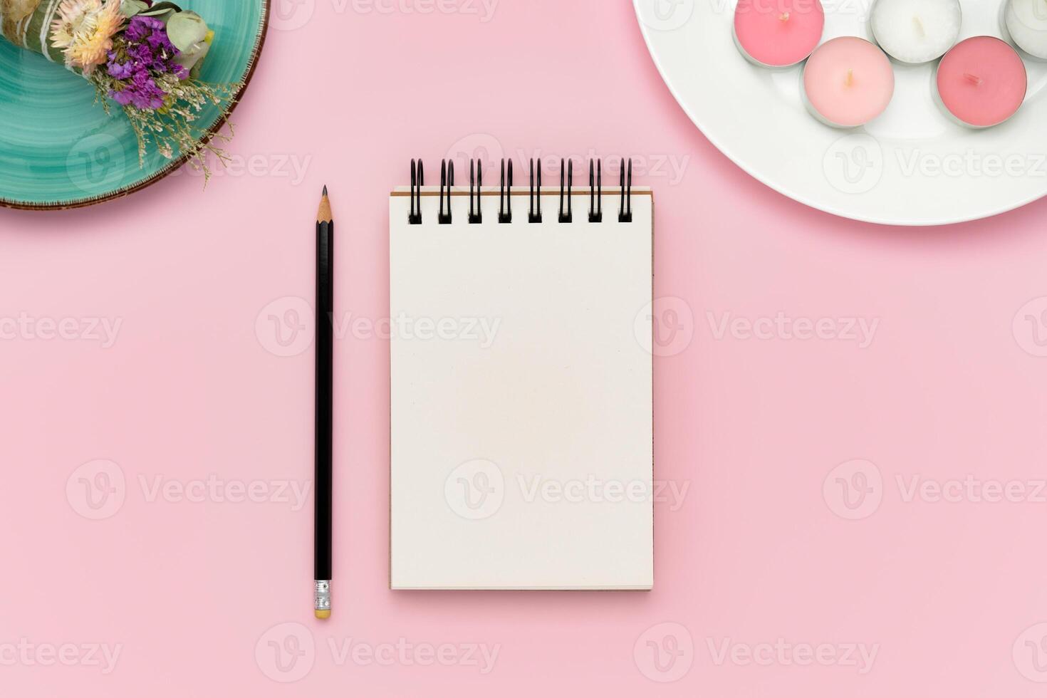 Blank notebook and pencil on pink background with pink candles and smudge stick photo