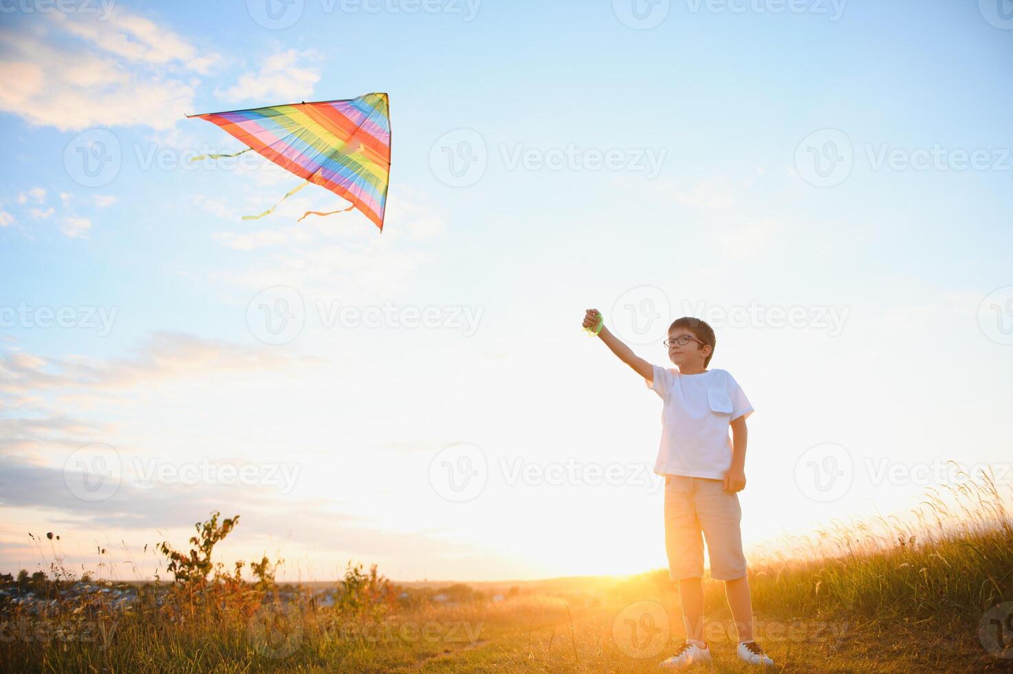 Boy is running with a kite during the day in the field photo