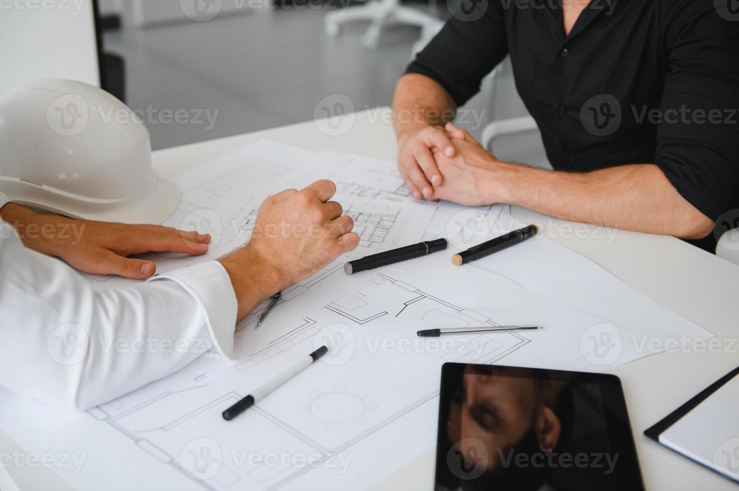 two people sit in front of construction plan and talk about the architecture photo