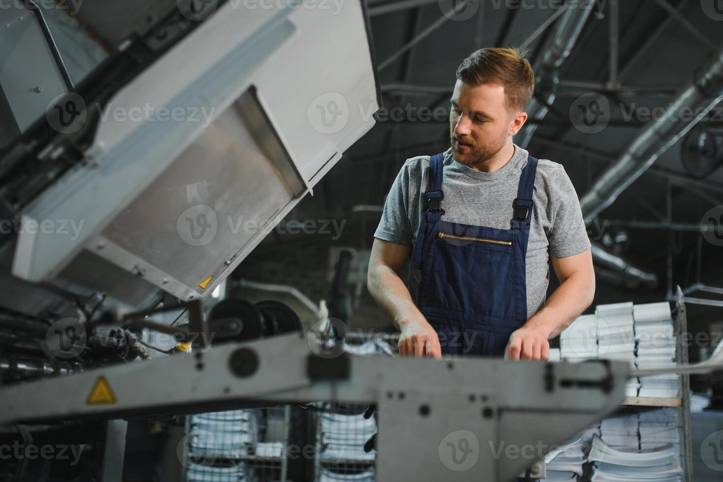 worker in protective clothing in factory using machine photo