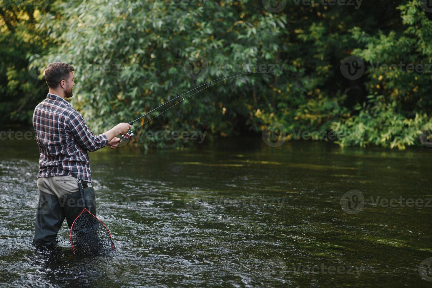 Fisherman catches a trout on the river in summer photo