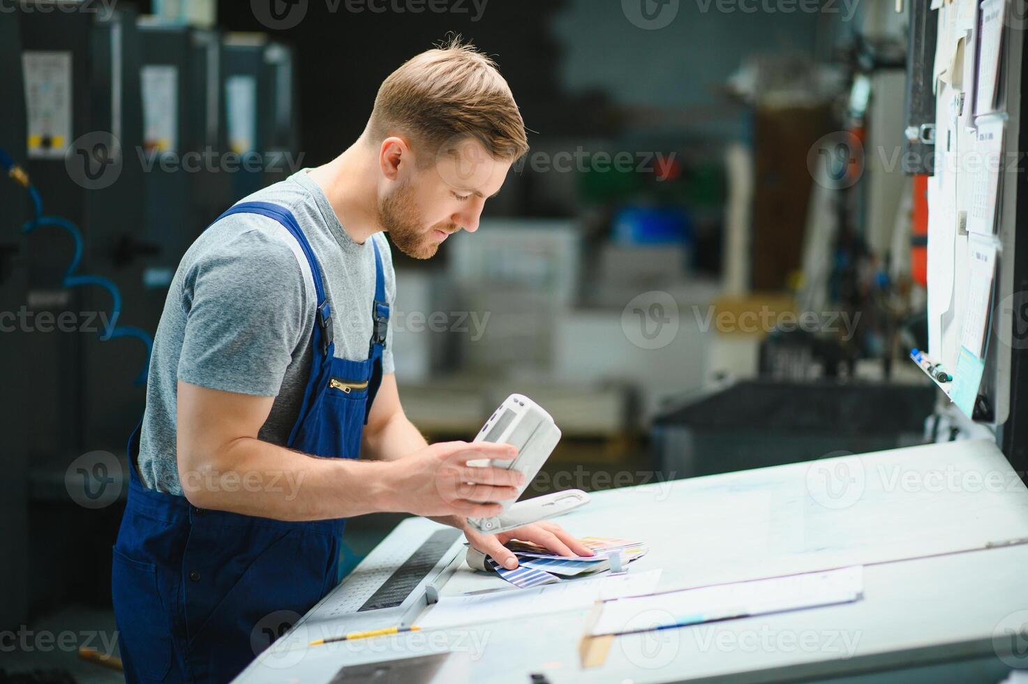 Portrait of production line worker controlling manufacturing process of modern packaging industrial machine in printing factory photo