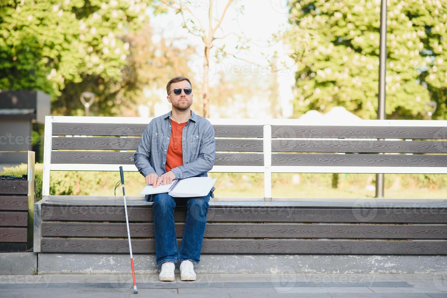 Blind man reading book on bench in park photo