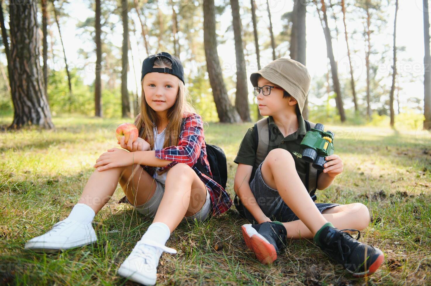 boy and girl go hiking with backpacks on forest road bright sunny day photo