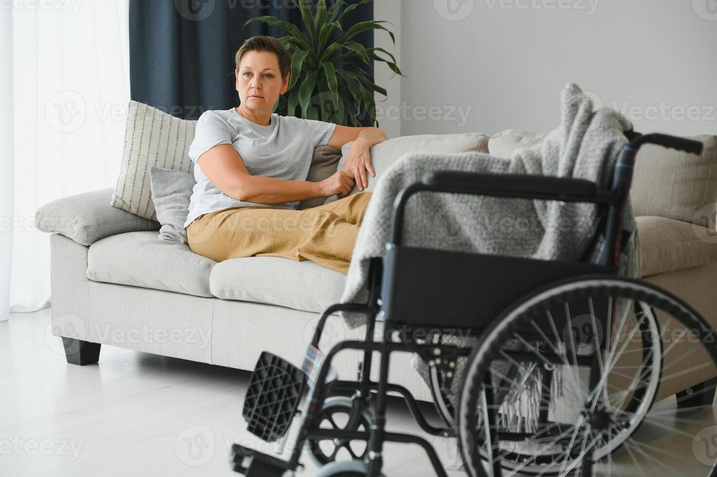 Brunette woman on couch near wheelchair photo