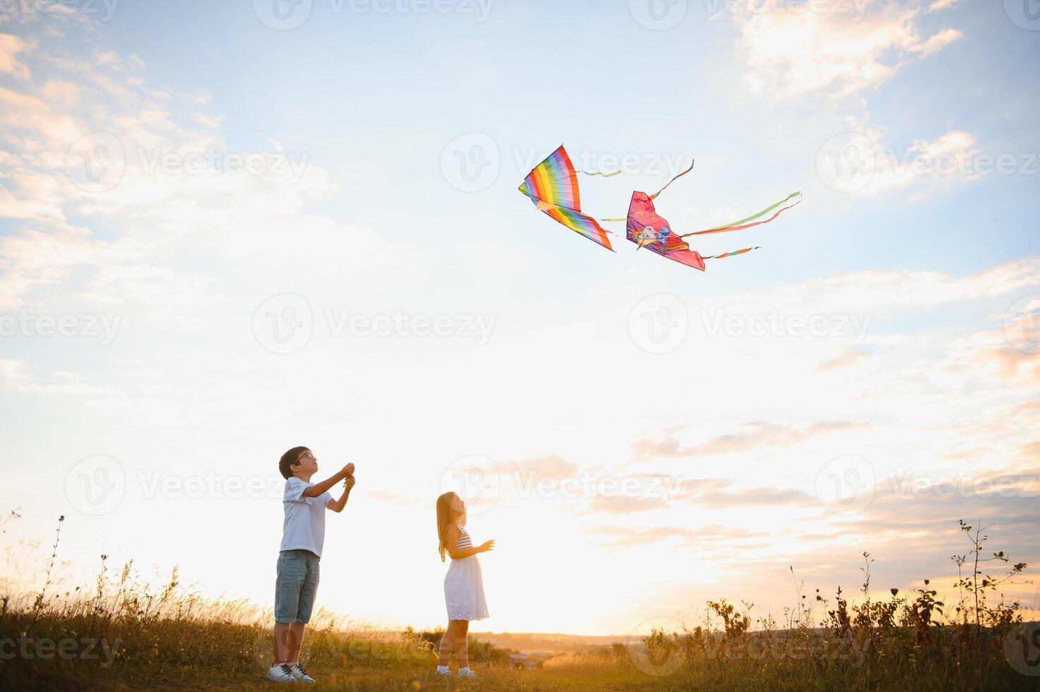 Children launch a kite in the field at sunset photo