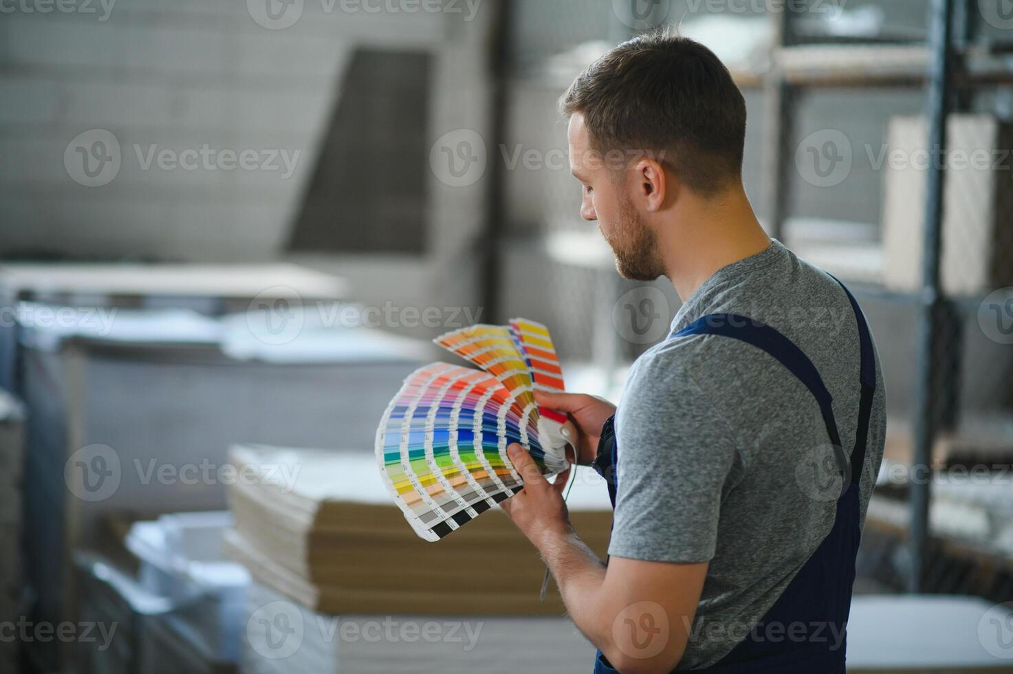 Man working in printing house with paper and paints photo