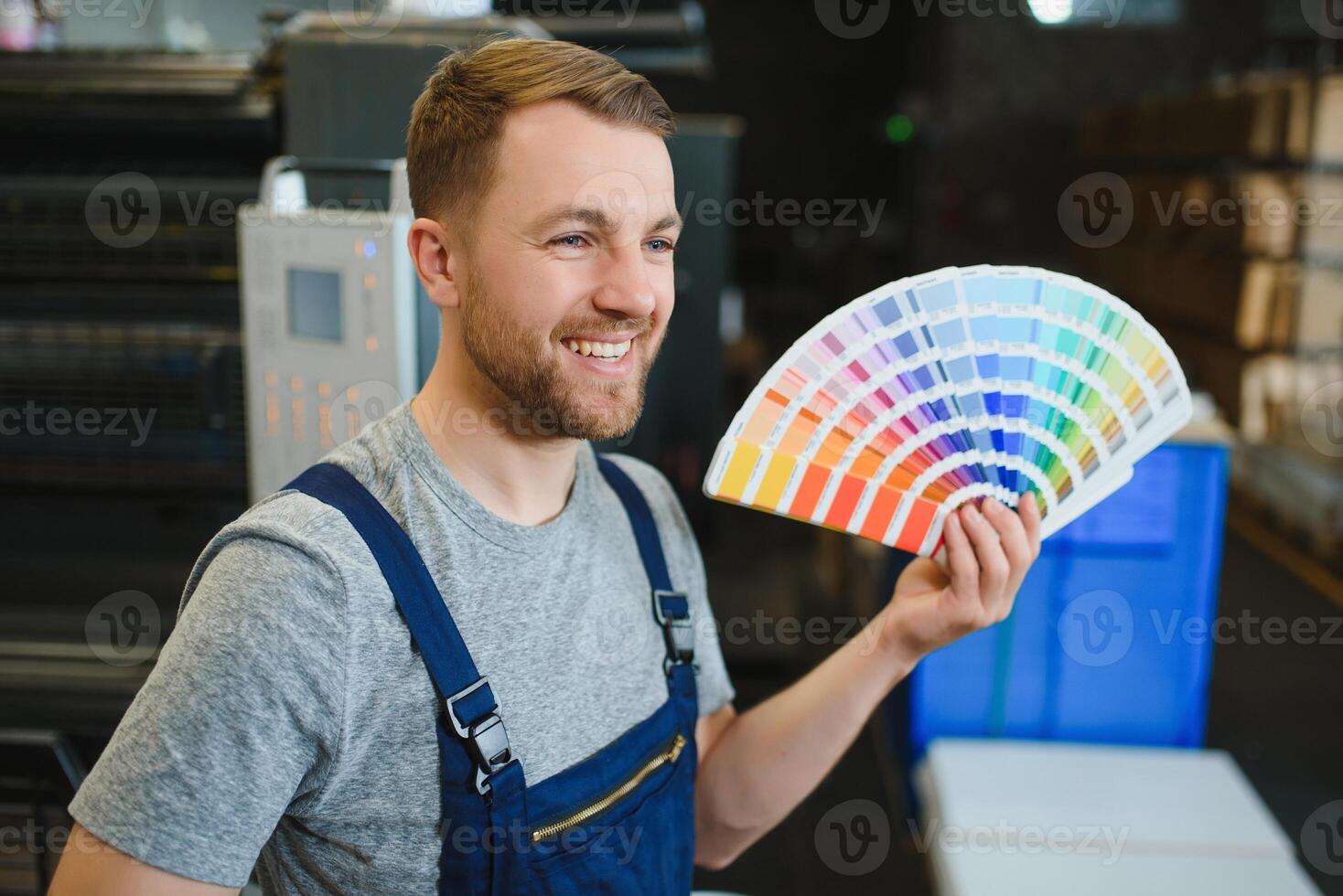 Man working in printing house with paper and paints photo