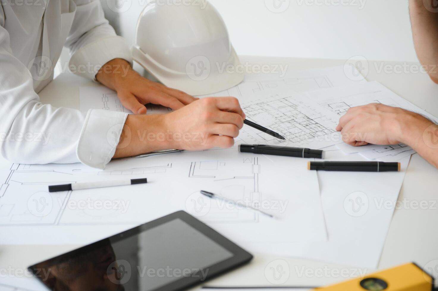 Two engineering working together and using digital tablet looking blueprint and analysis with architectural plan on desk photo