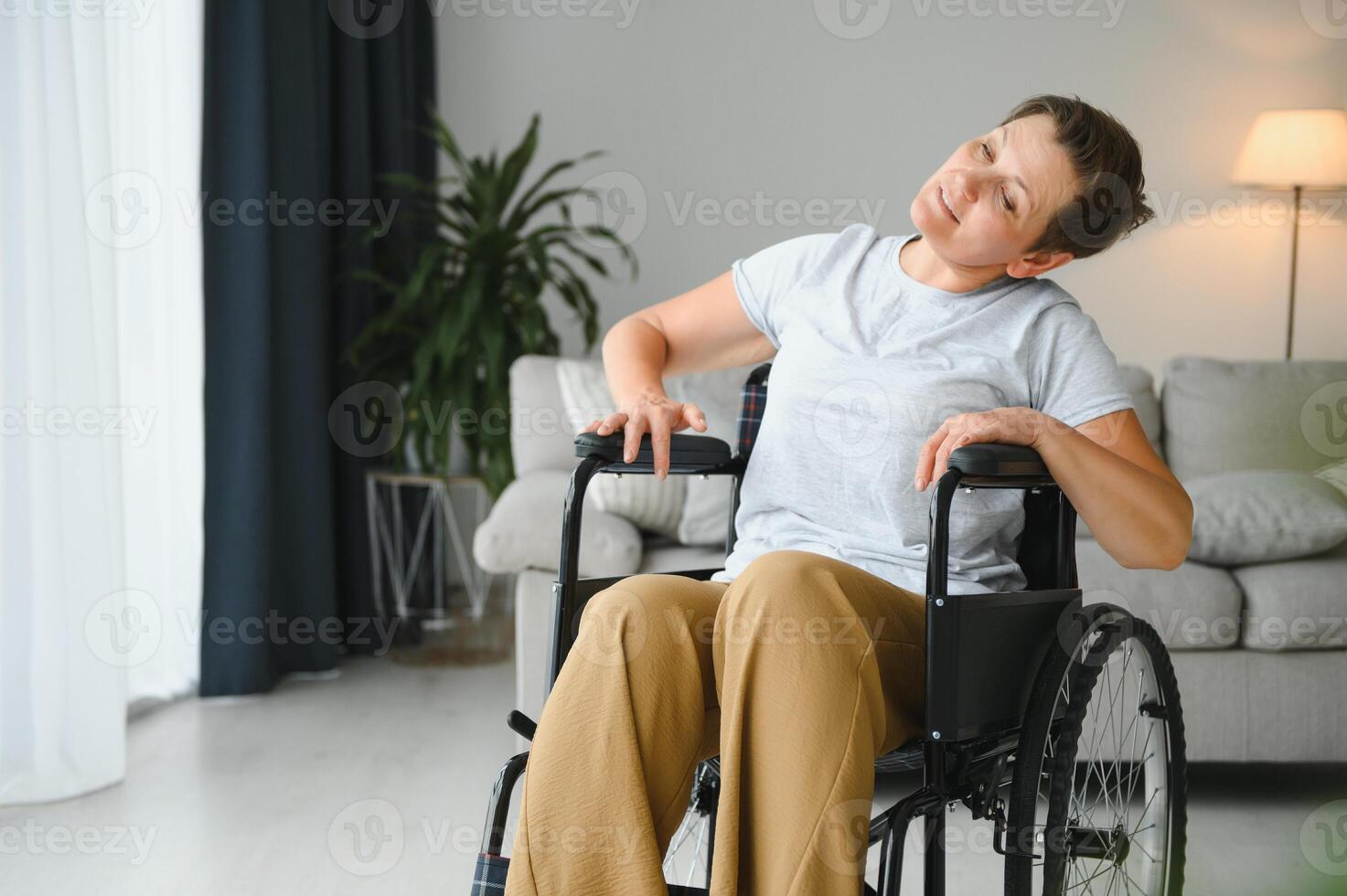 Woman in wheelchair working out in living room photo