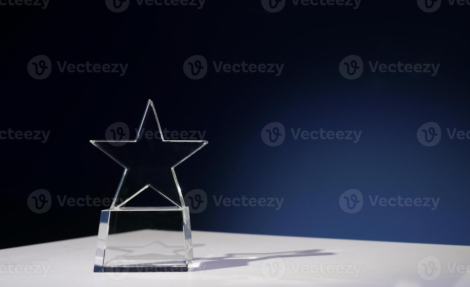 Star-shaped award made of glass on a white table with a spotlight on it and copy space photo