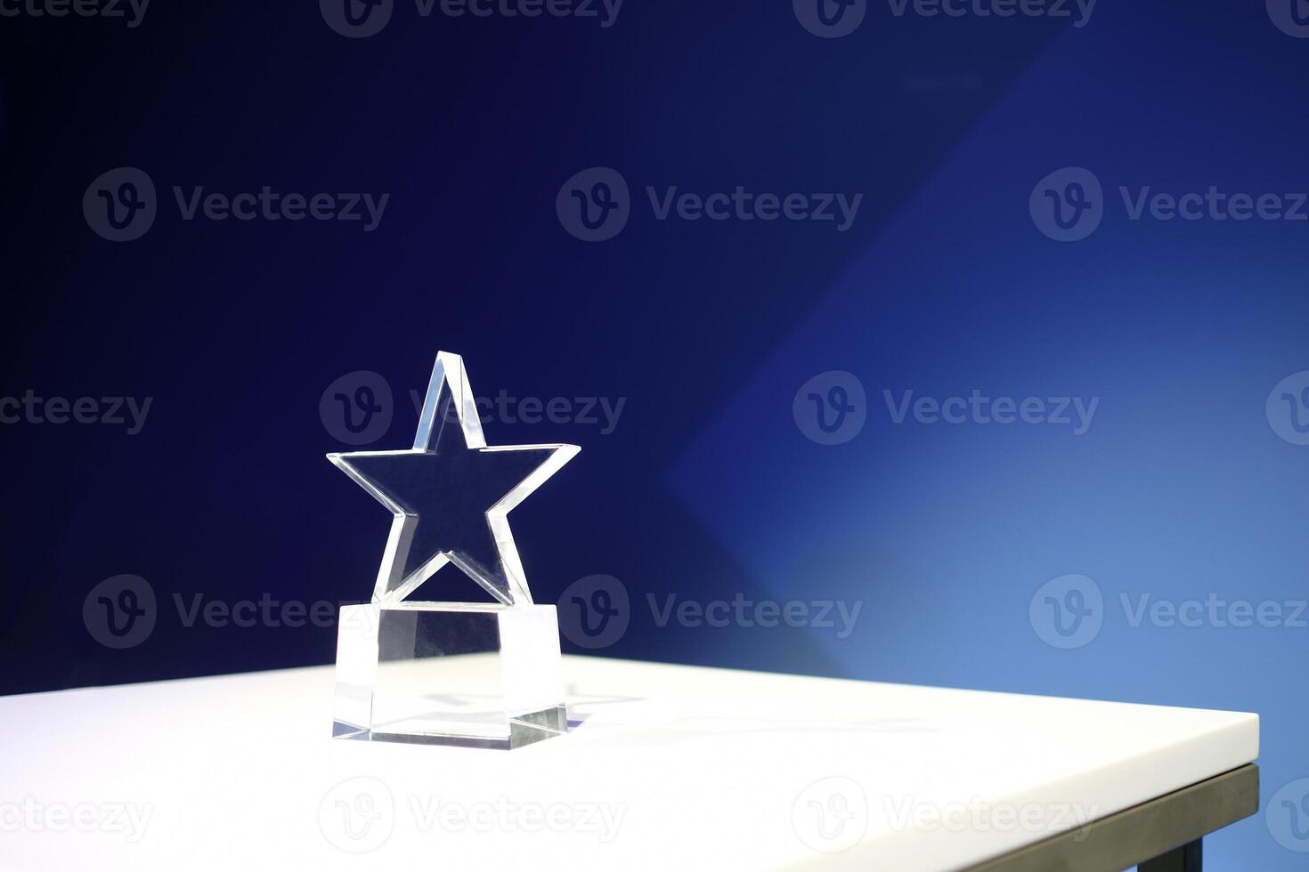 Star-shaped award made of glass on a white table with a spotlight on it and copy space photo