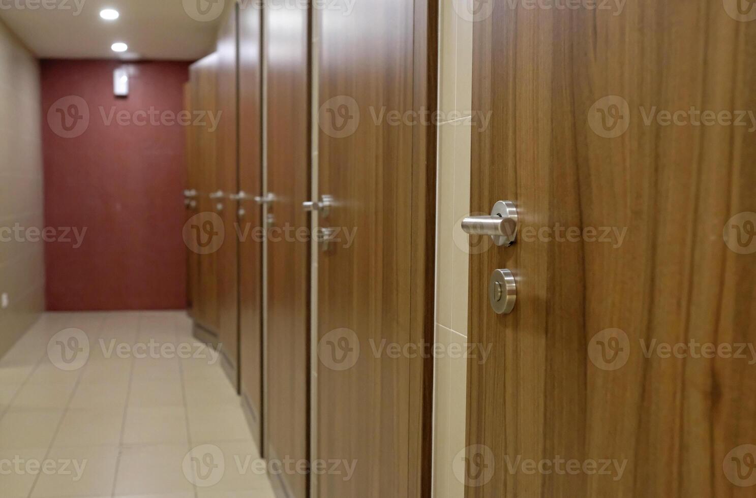 Multiple stalls with wooden doors in a row in a bathroom photo