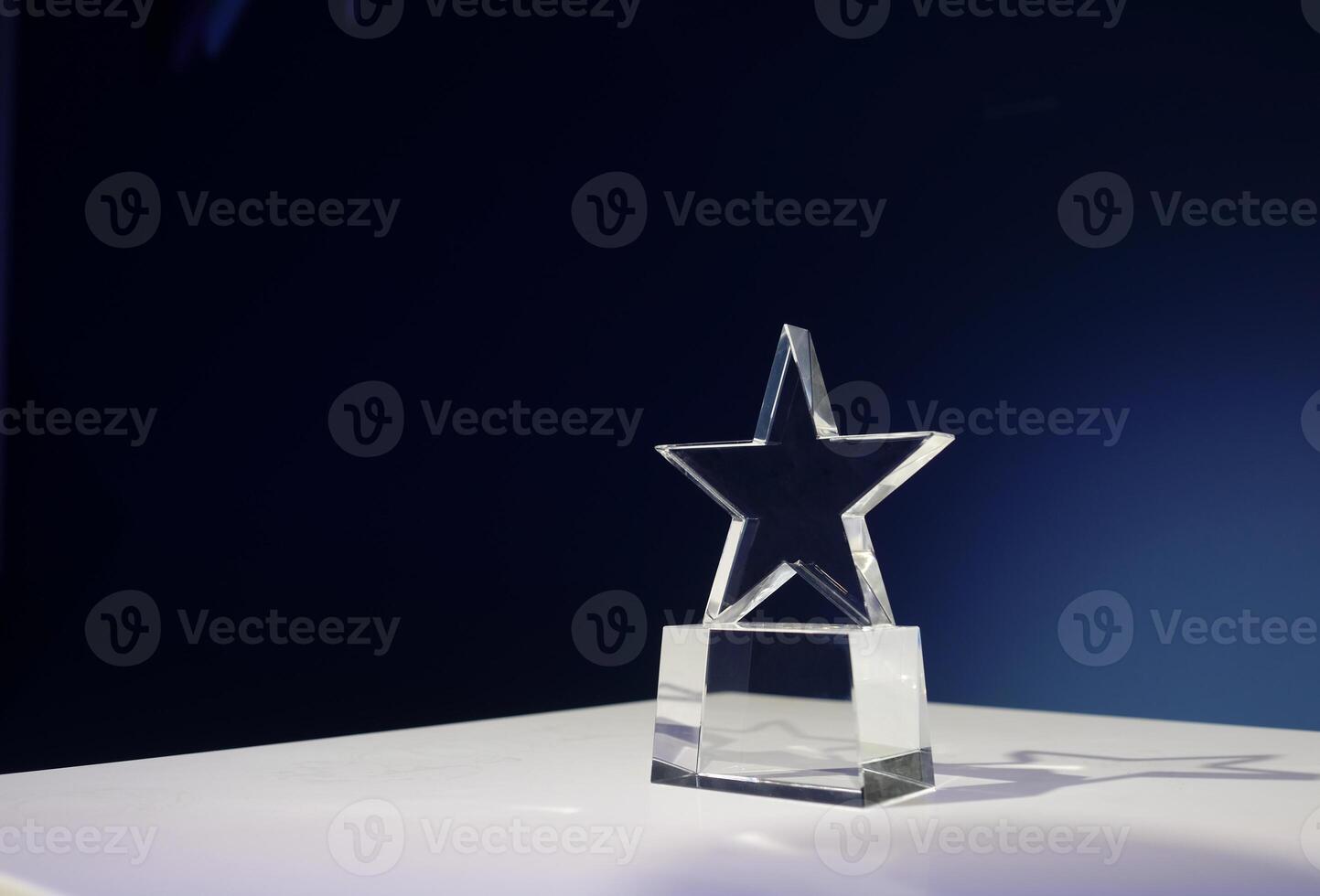 Star-shaped award made of glass on a white table with a spotlight on it and copy space photo