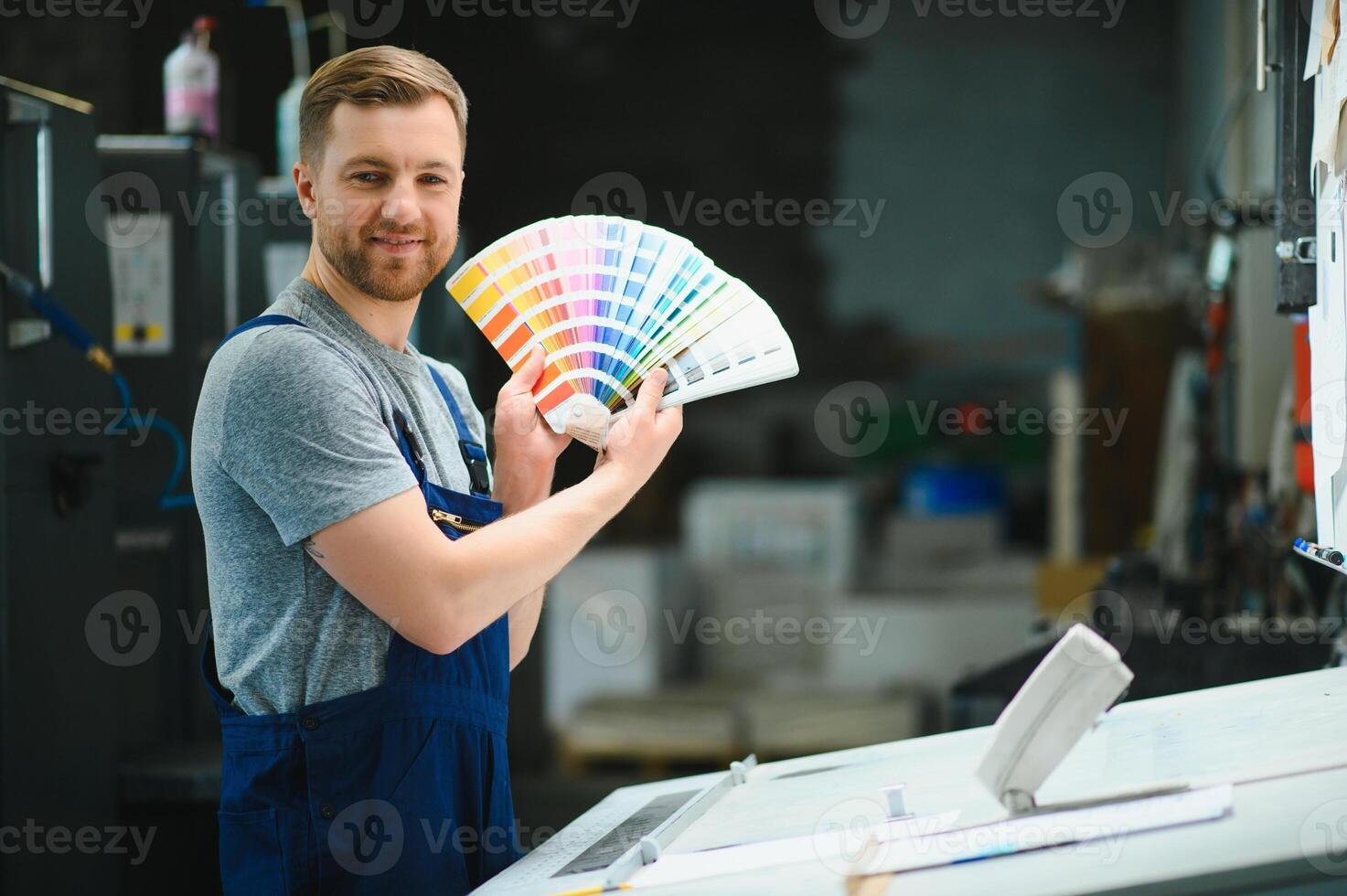 Man working in printing house with paper and paints photo