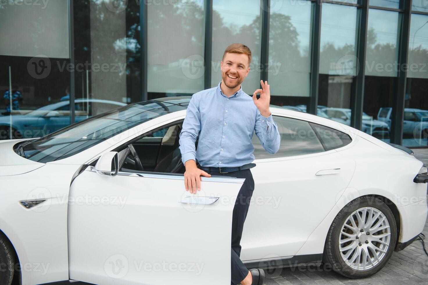 hermoso joven empresario en pie cerca su coche al aire libre. foto