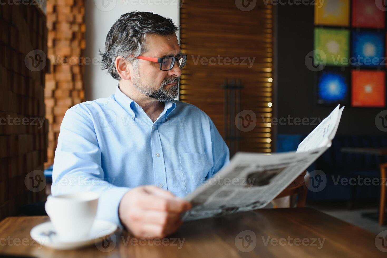 active senior man reading newspaper and drinking coffee in restaurant photo