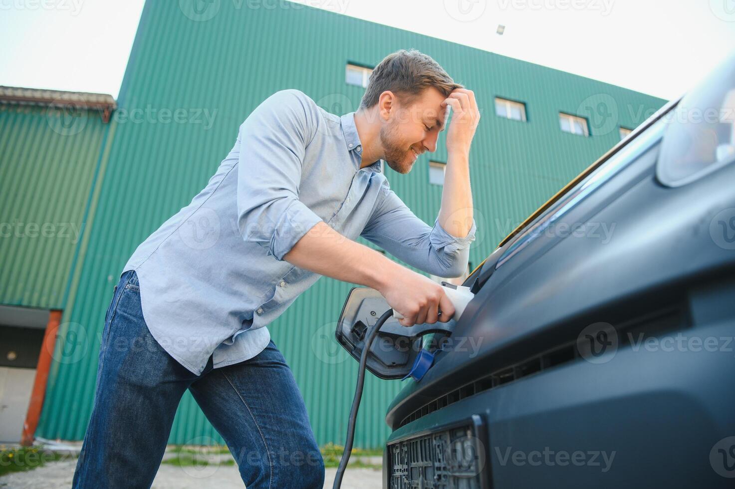 Smiling man unplugging the charger from the car photo