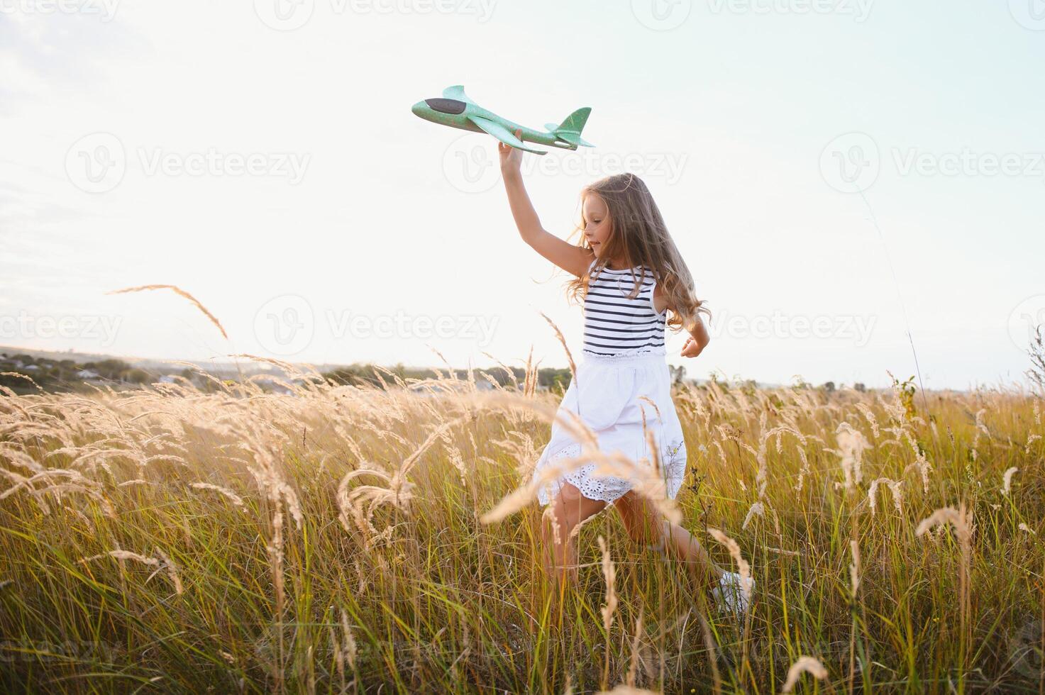 Happy kid with toy plane is playing at sunset photo