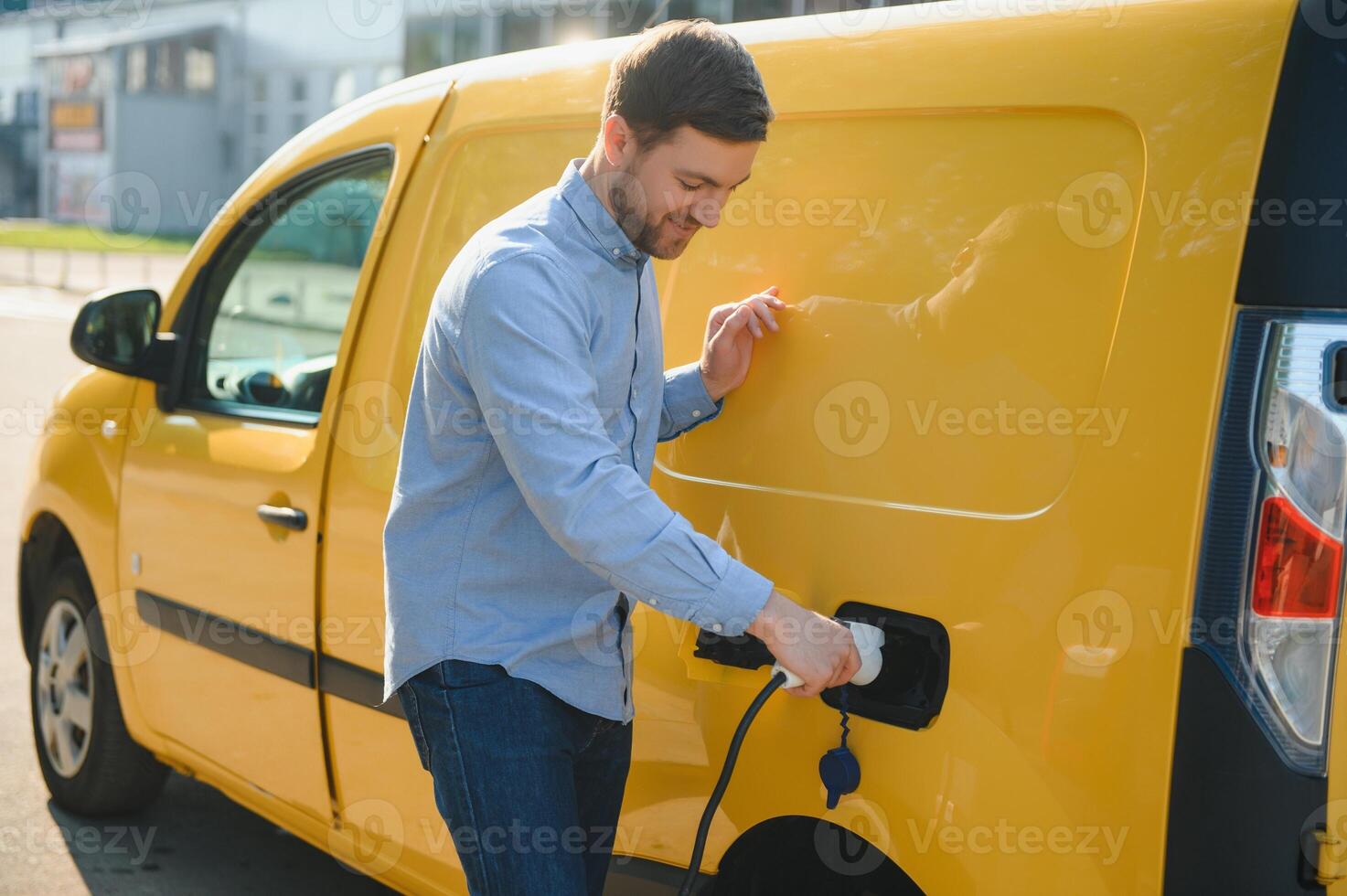 Smiling man unplugging the charger from the car photo