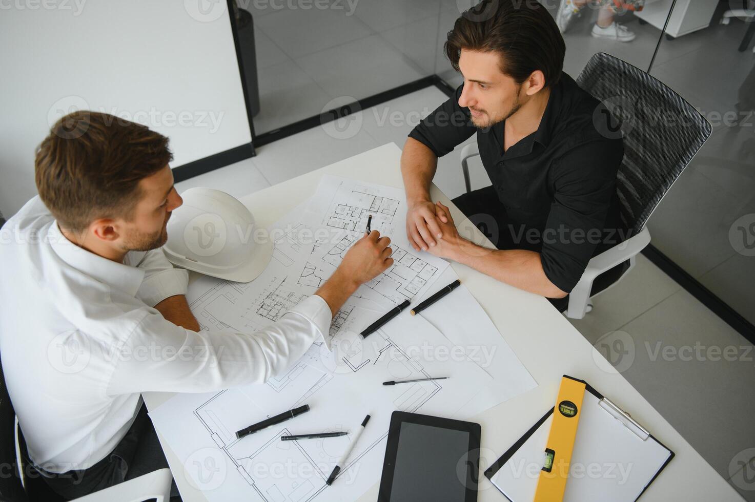 two people sit in front of construction plan and talk about the architecture photo