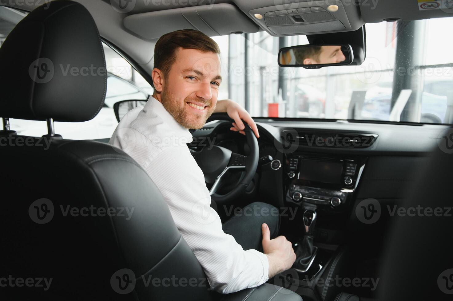 Taxi driver smiling while turning over to the backseat looking talking with clients. Successful businessman husband looking at the backseat at dealer shop before buying a car photo