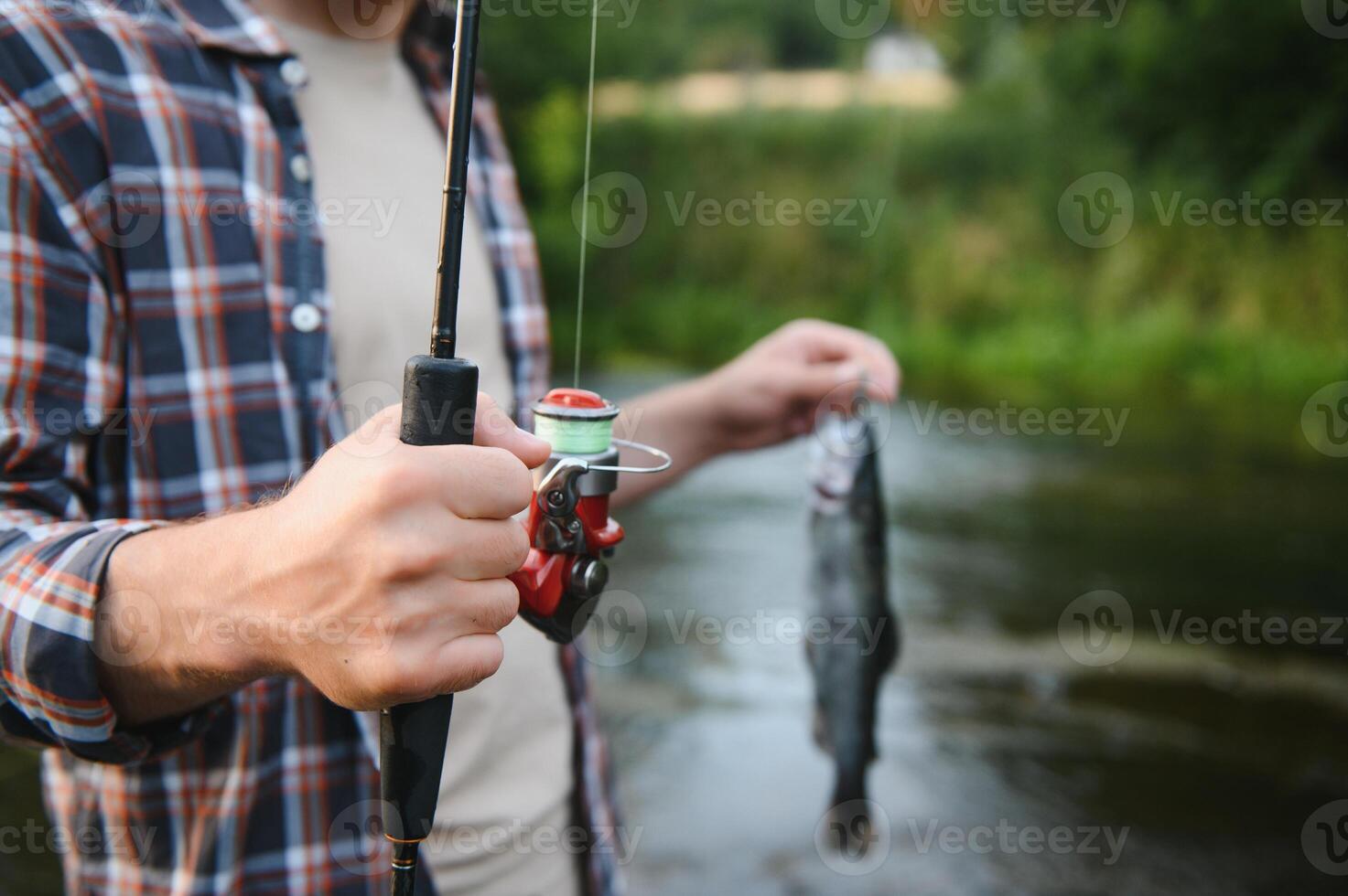 Fly-fisherman holding trout out of the water photo