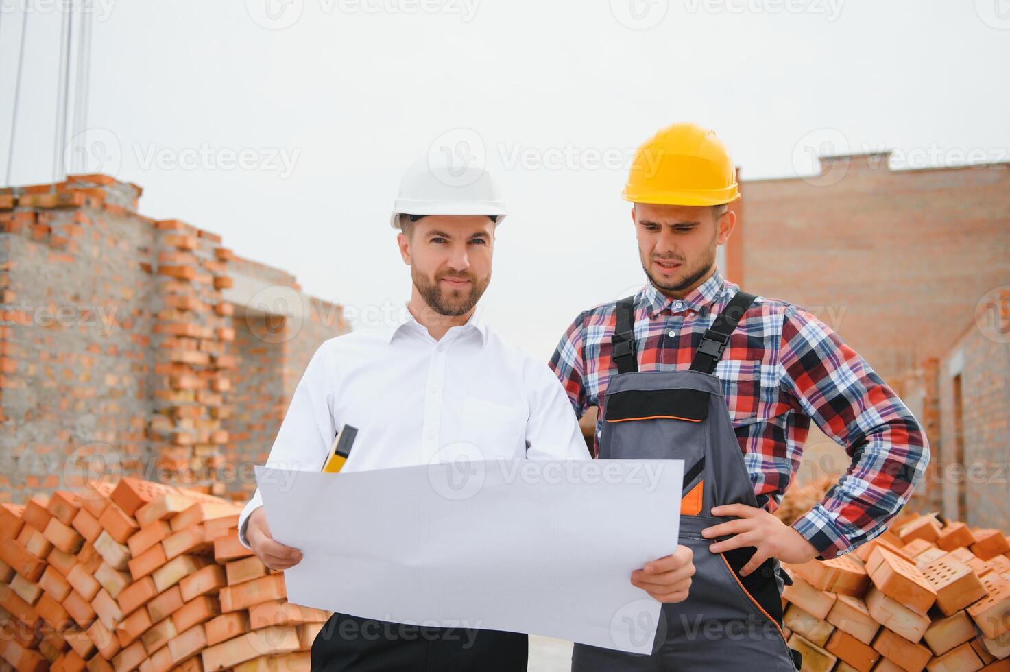 engineer architect with hard hat and safety vest working together in team on major construction site photo