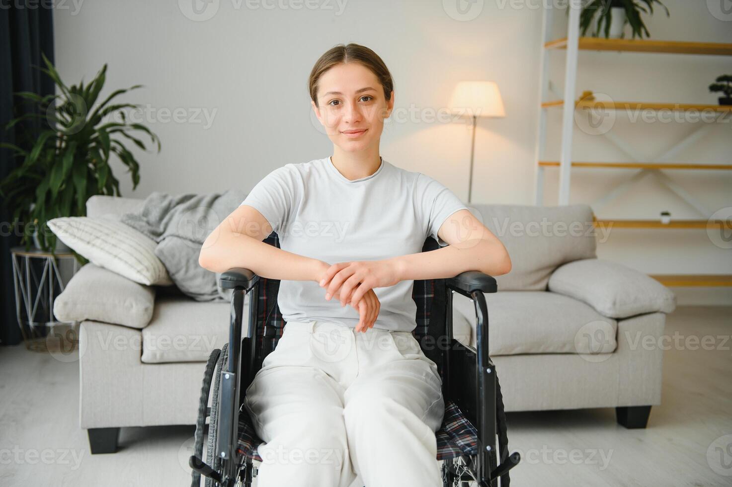 Young woman in wheelchair at home in living room. photo