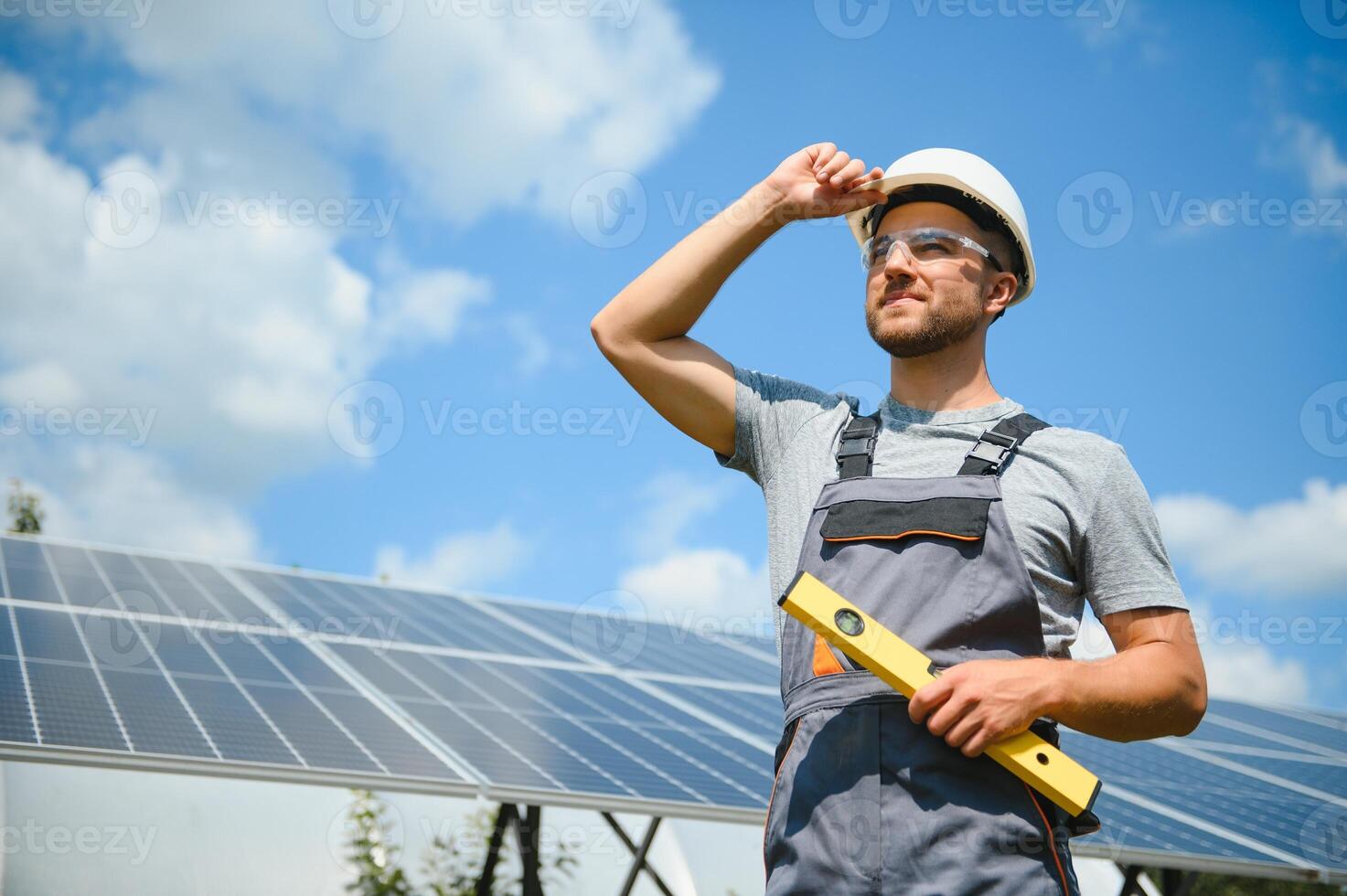 Male worker with solar batteries. Man in a protective helmet. Installing stand-alone solar panel system photo