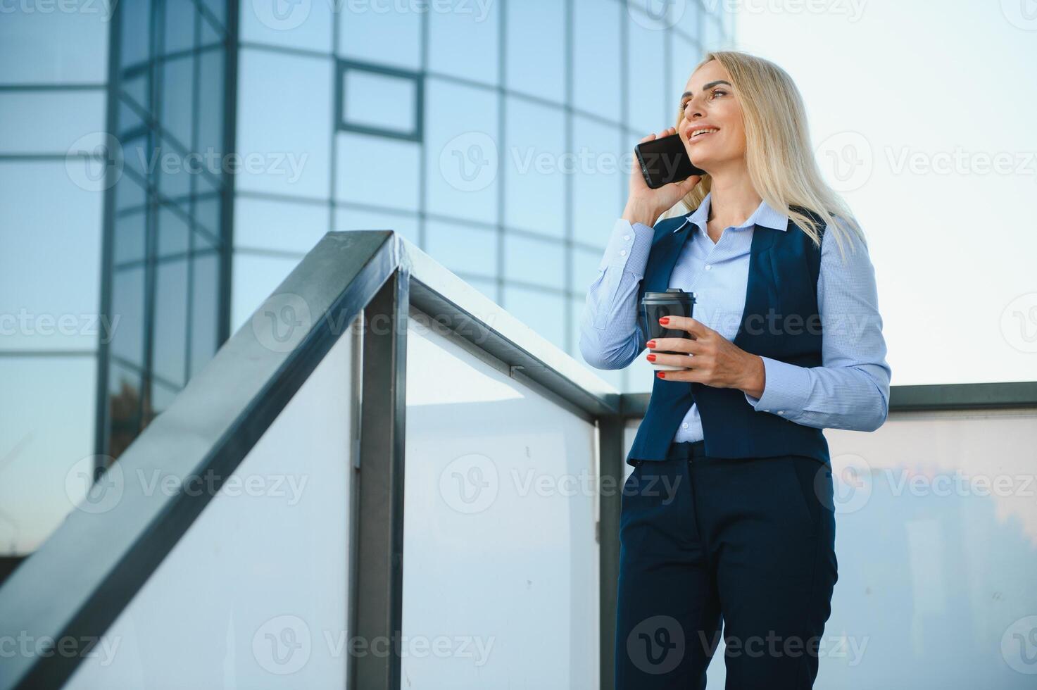 hermosa mujer yendo a trabajo con café caminando cerca oficina edificio. retrato de exitoso negocio mujer participación taza de caliente beber. foto