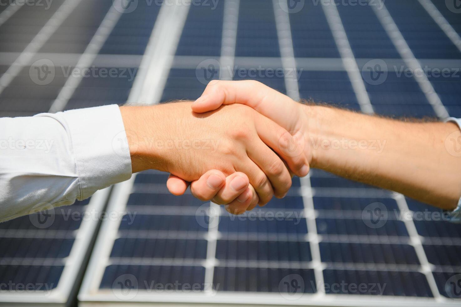 Two people having a shaking hands against solar panel after the conclusion of the agreement in the renewable energy photo