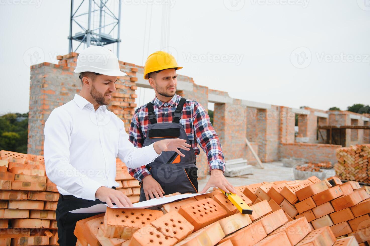Construction engineers supervising progress of construction project stand on new concrete floor top roof and crane background. photo