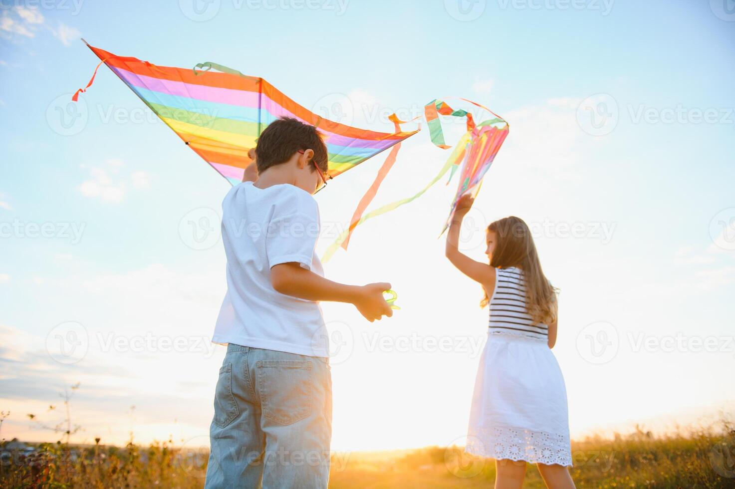 Brother and sister playing with kite and plane at the field on the sunset. photo