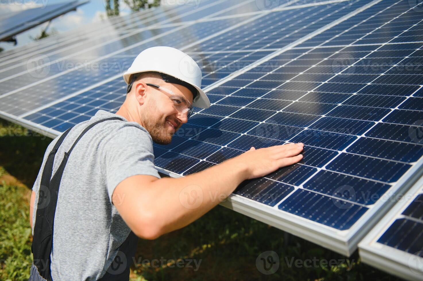 Male worker with solar batteries. Man in a protective helmet. Installing stand-alone solar panel system photo