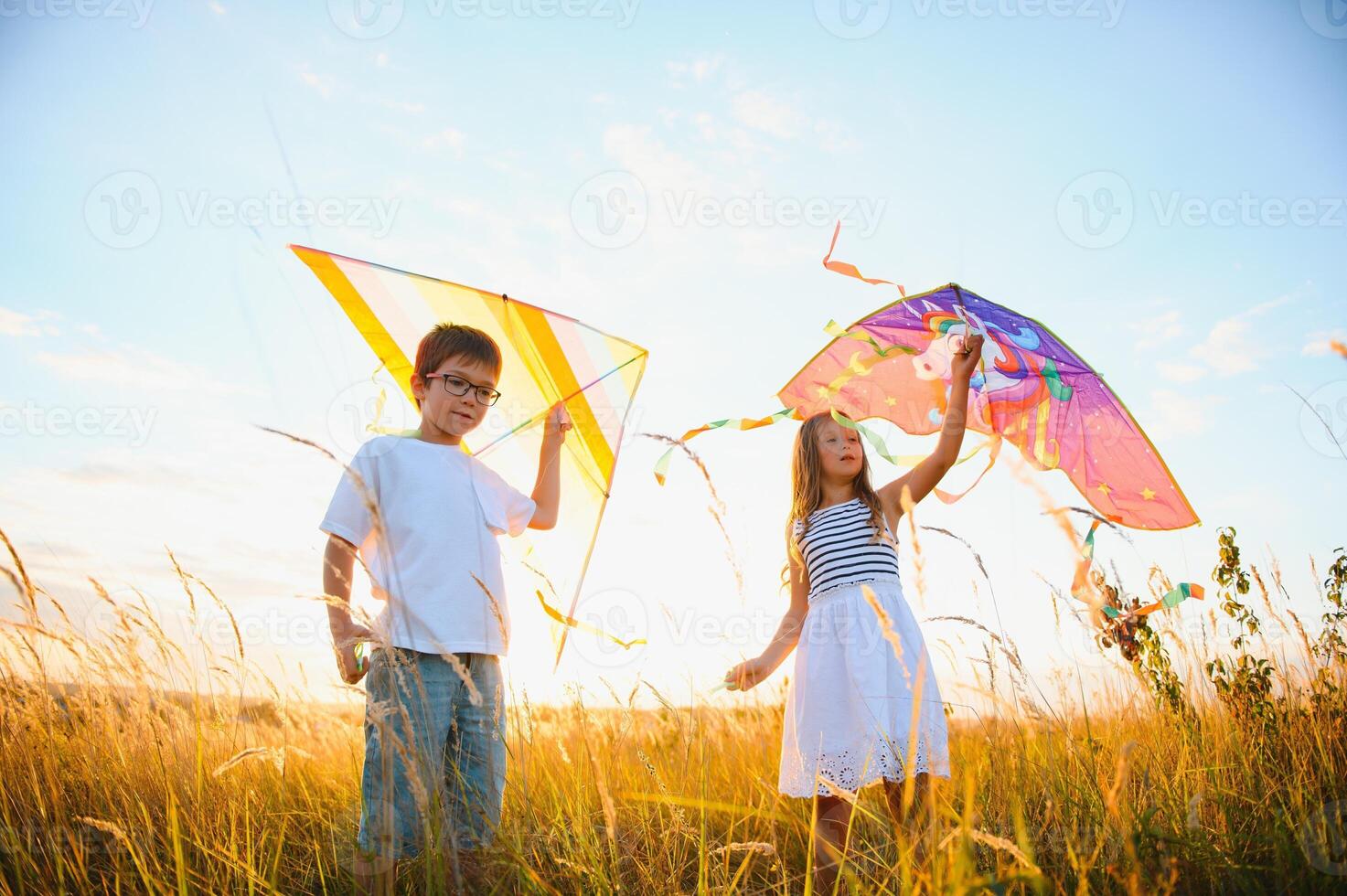 Children launch a kite in the field at sunset photo