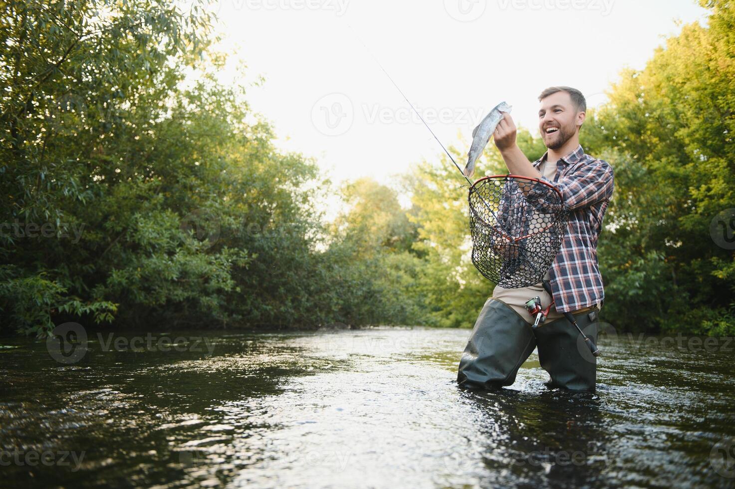 Fly-fisherman holding trout out of the water photo