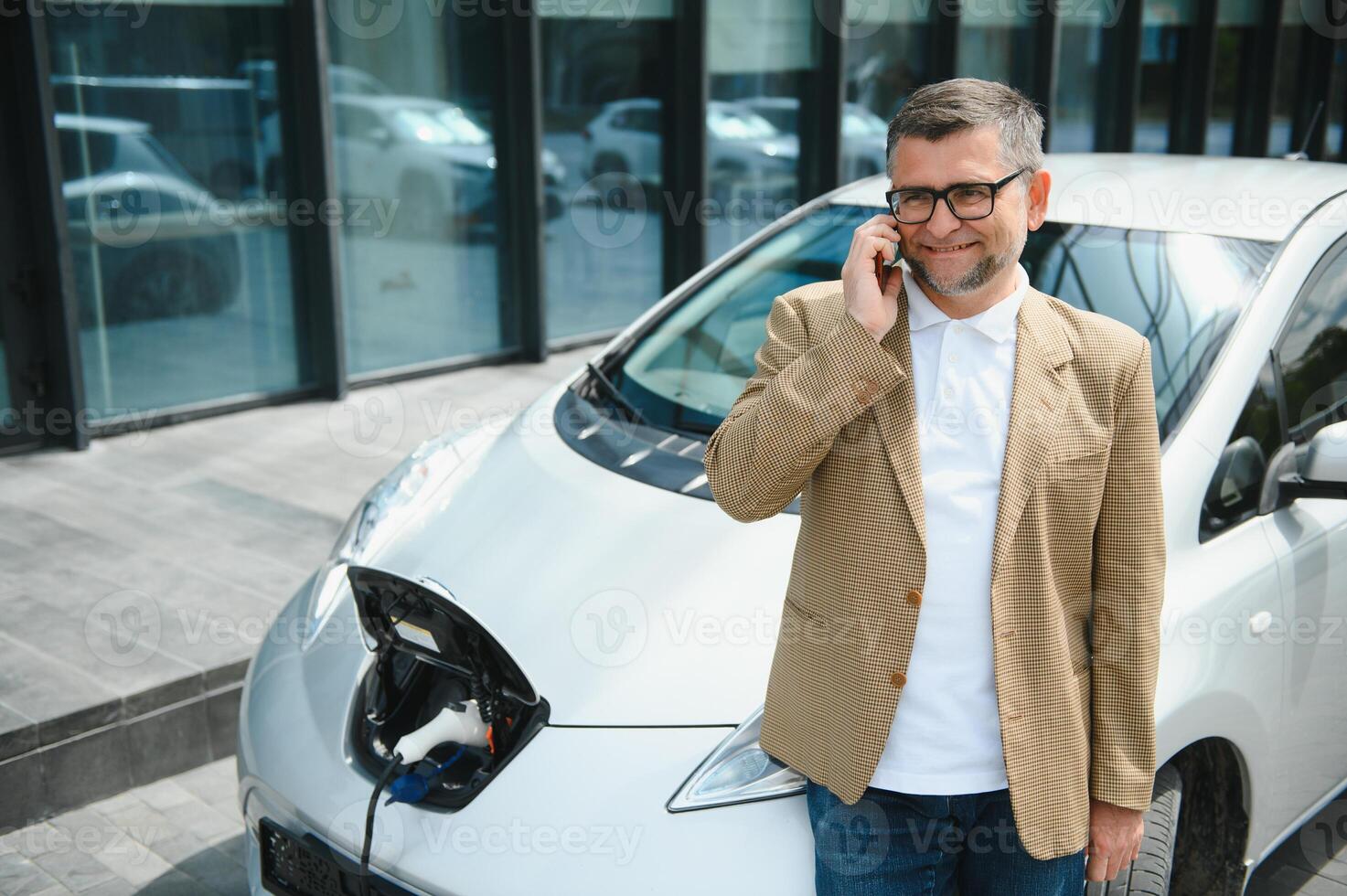 Handsome man using phone while car being charged photo