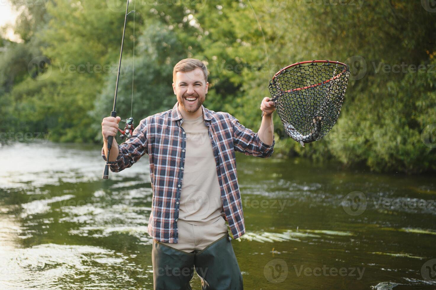 Fly-fisherman holding trout out of the water photo