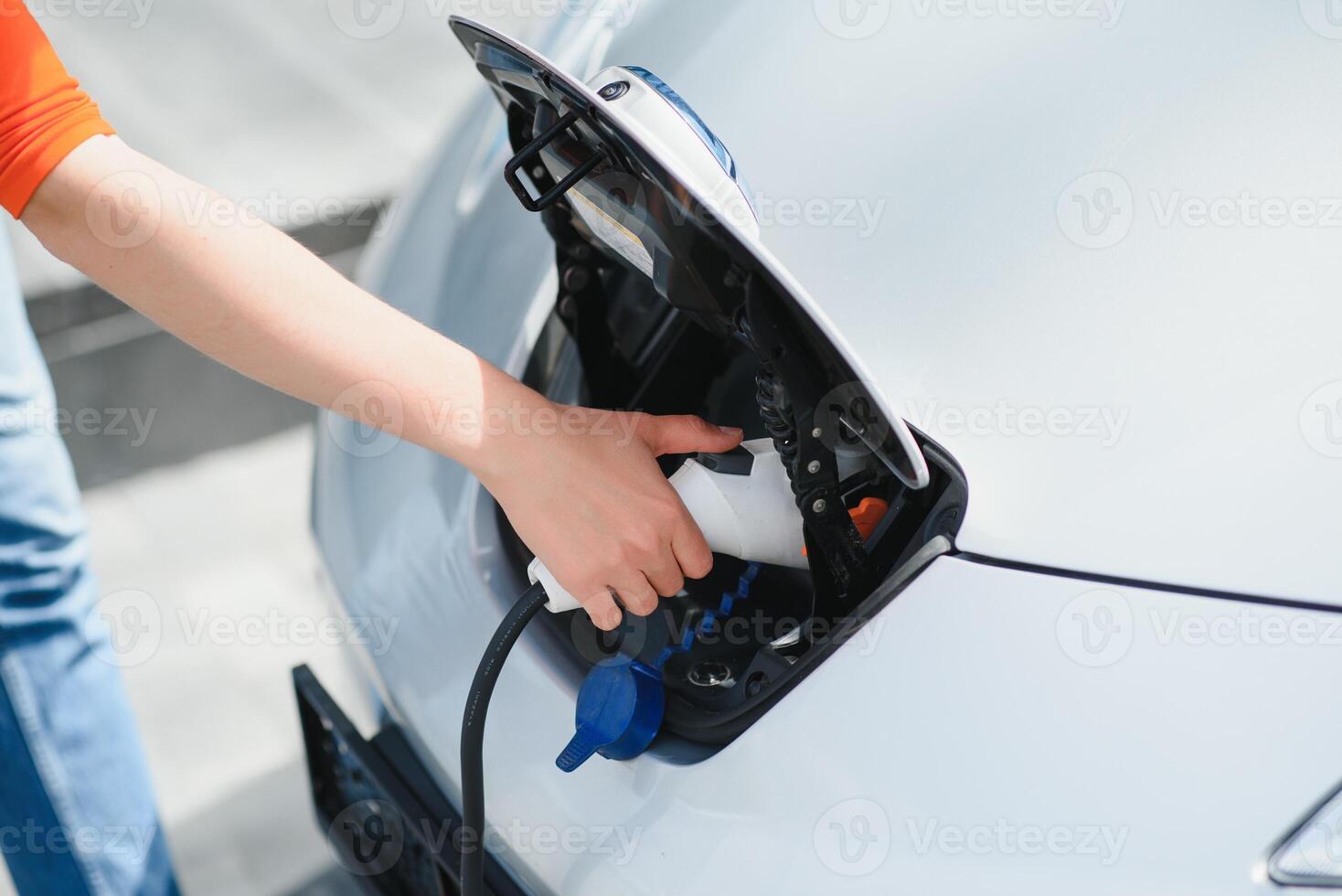 Charging car. Young woman in casual clothes with her electromobile outdoors at daytime photo