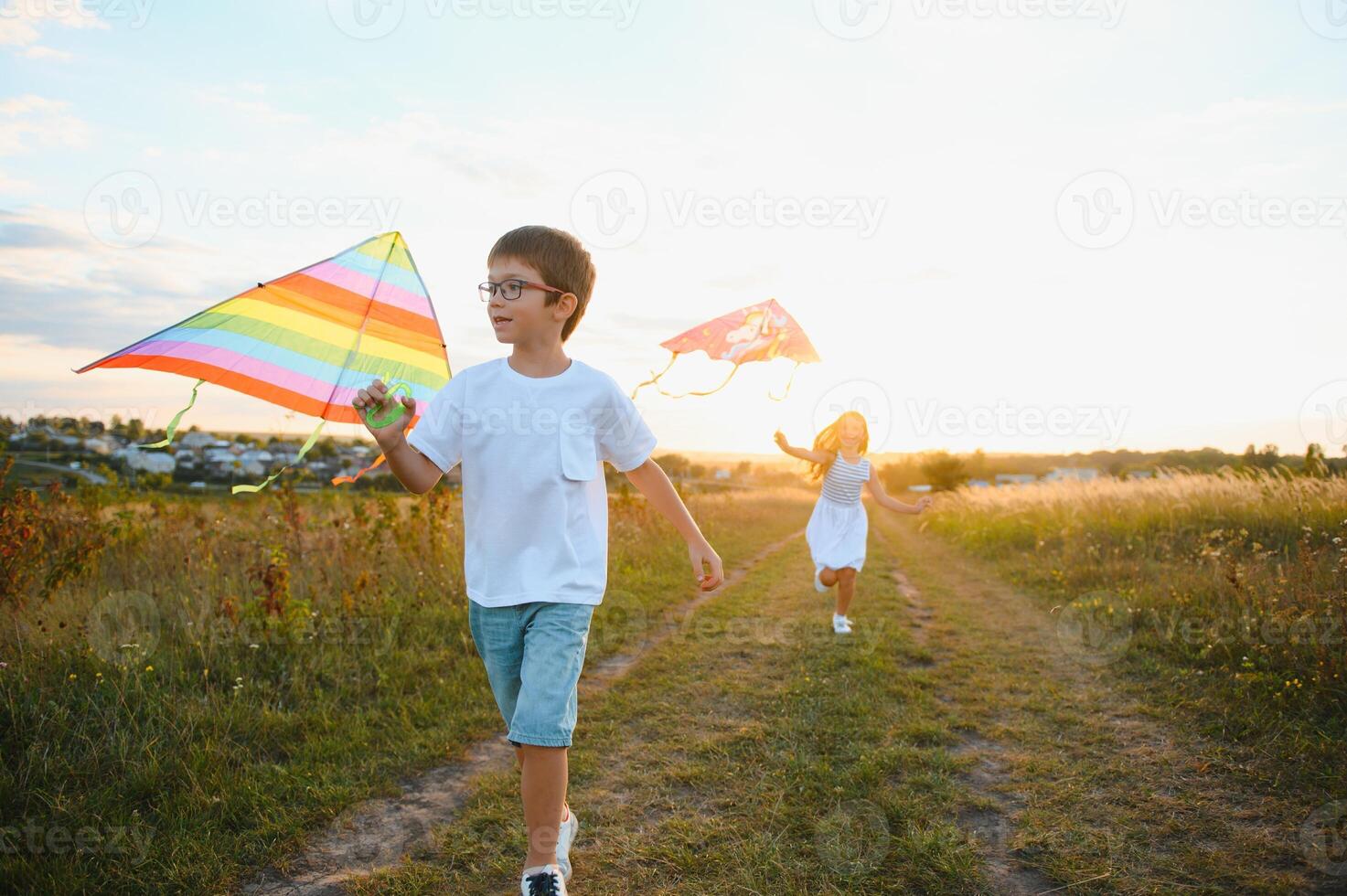 Happy children launch a kite in the field at sunset. Little boy and girl on summer vacation. photo