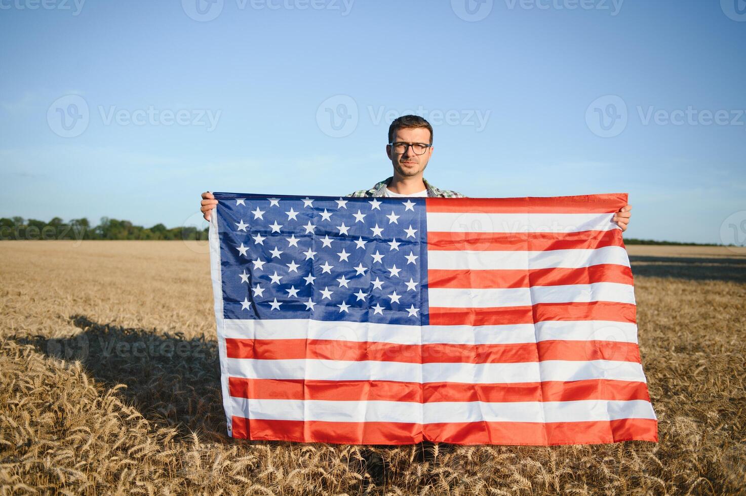 joven hombre participación americano bandera, en pie en trigo campo foto