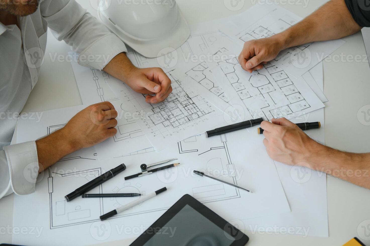 two people sit in front of construction plan and talk about the architecture photo