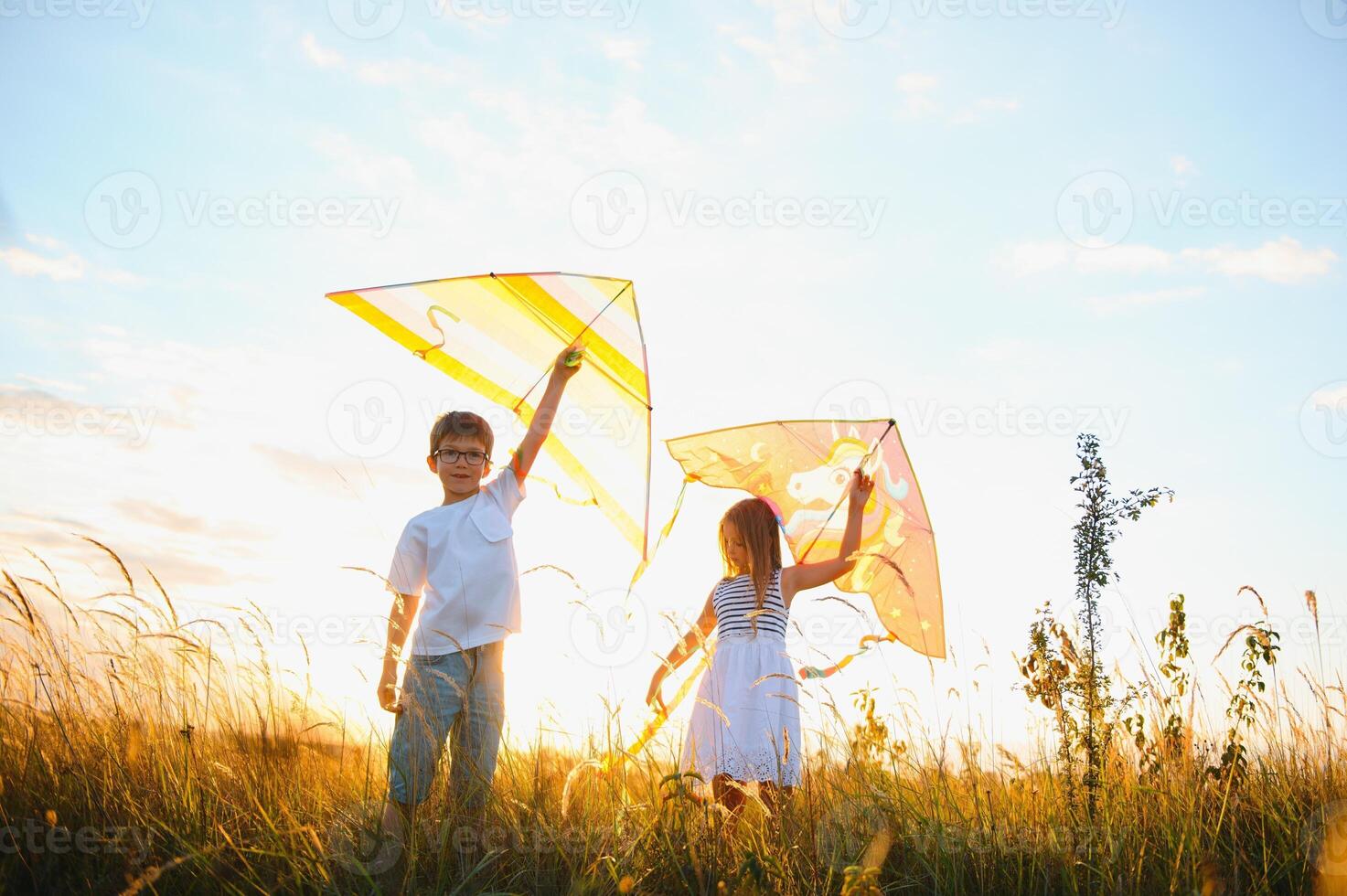 Happy children launch a kite in the field at sunset. Little boy and girl on summer vacation. photo