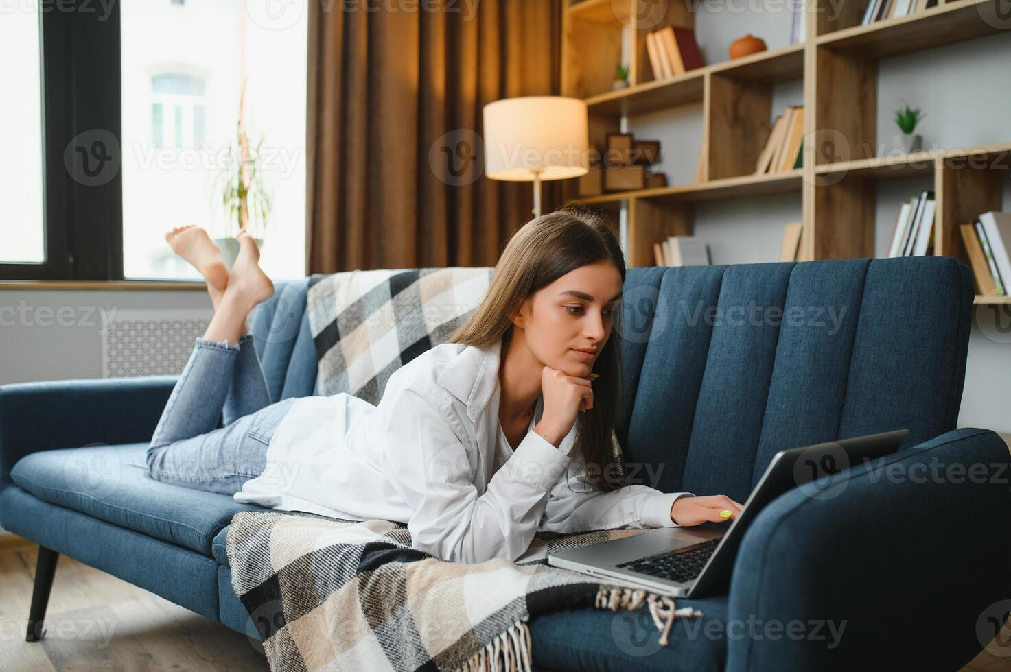 Young woman lying on couch with laptop. photo