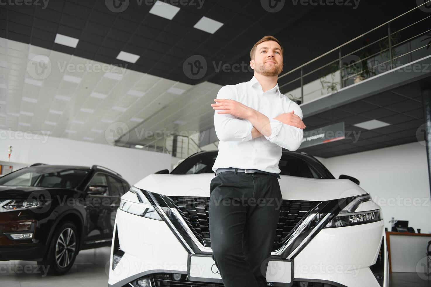 Young handsome man at show room standing near car photo