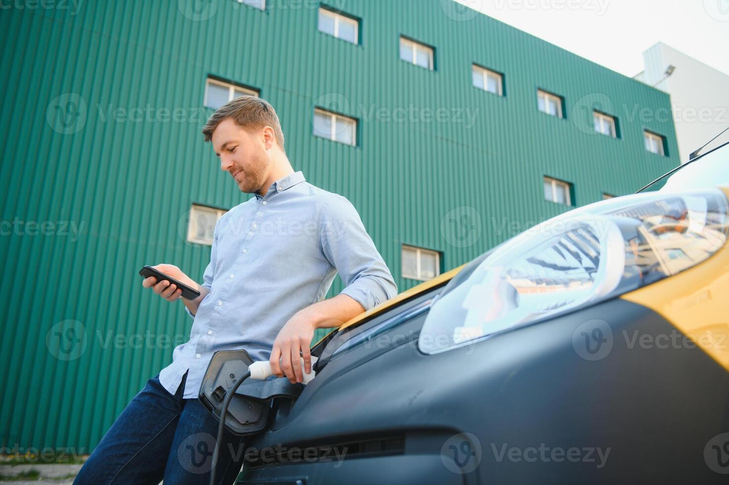 Smiling man unplugging the charger from the car photo